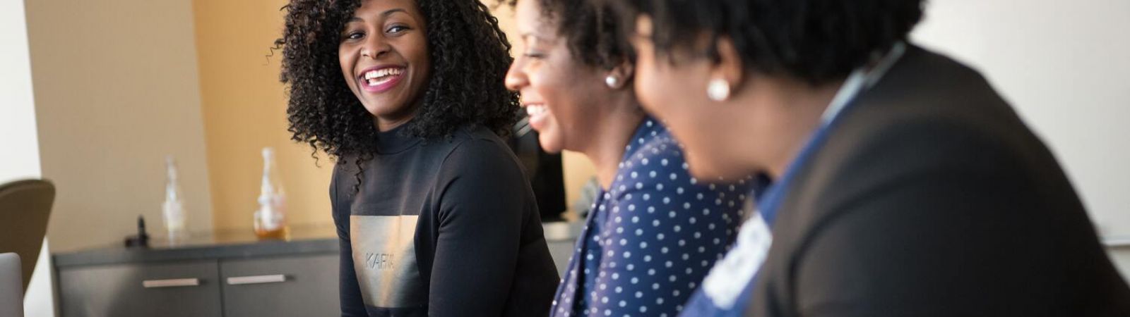 Trois femme assises àun bureau qui rient