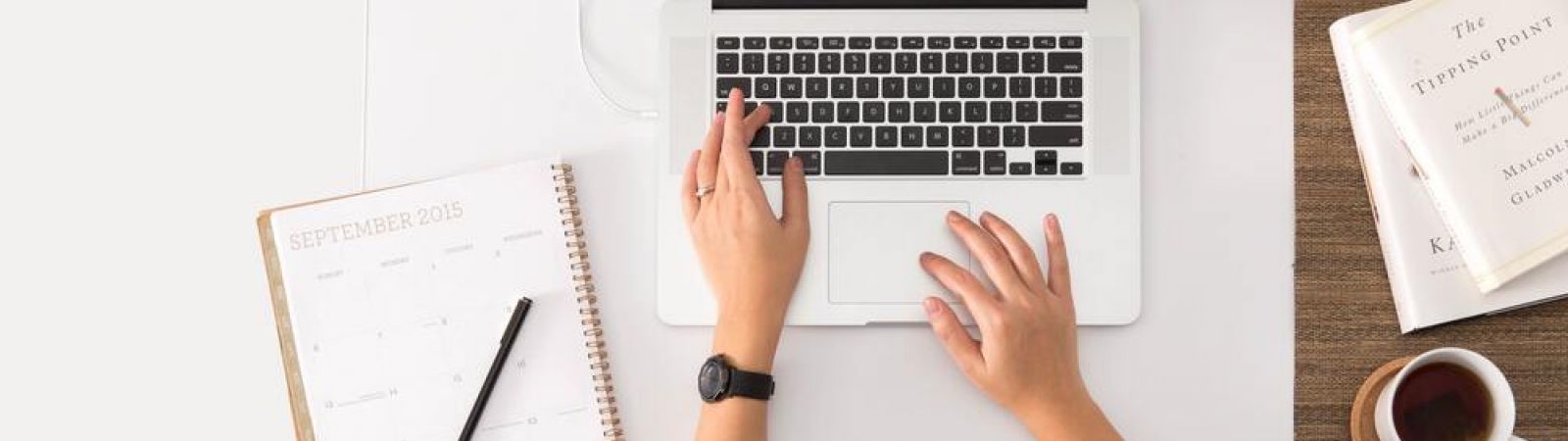 Vue en hauteur d'une femme assise à un burau qui tape au clavier d'un ordinateur portable