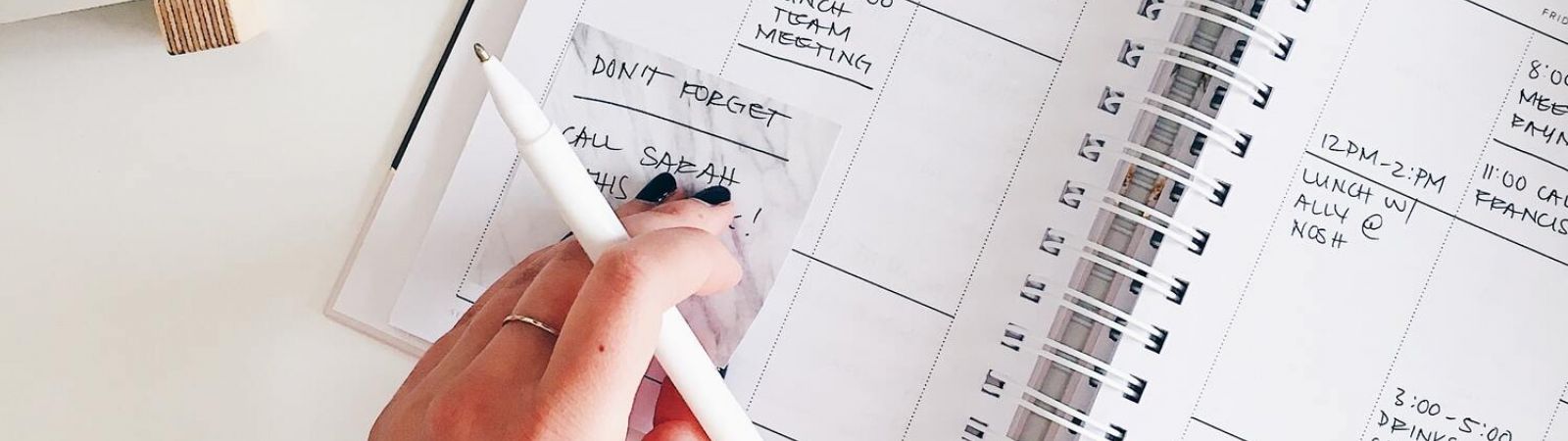 Vue hauteur d'une main avec un carnet et un stylo posé sur un bureau