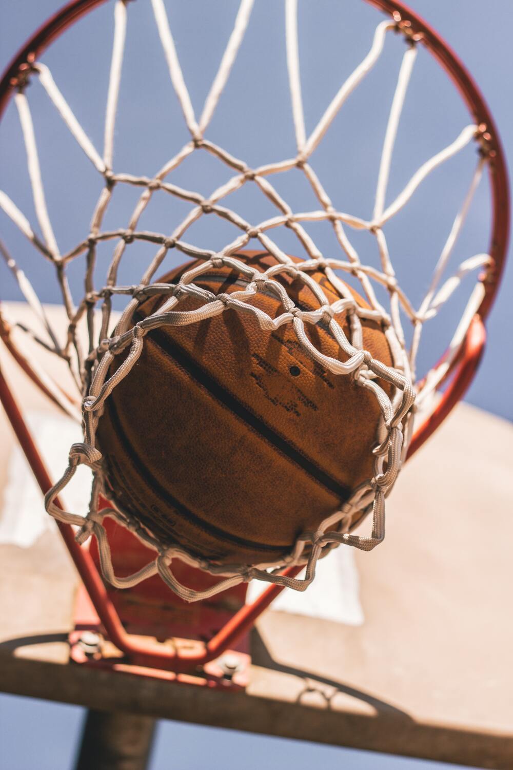 Vue contre plongée d'un ballon de basket qui rentre dans un panier de basket